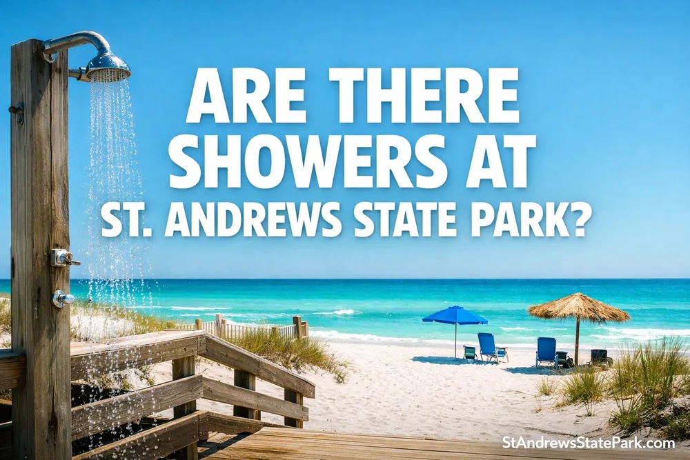 A shower structure at St. Andrews State Park with a sandy beach and a sailboat in the background.
